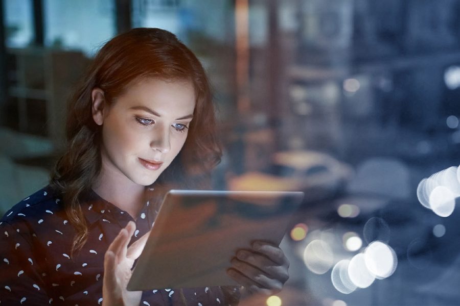 Woman looking at a bright tablet screen in a dim room