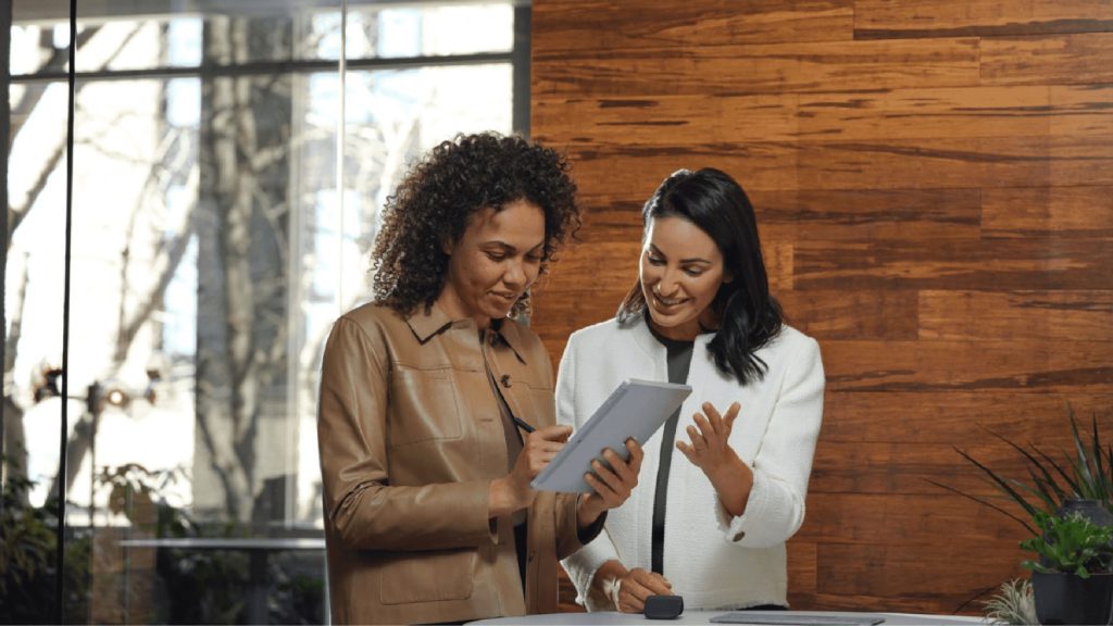 Two woman smiling, looking at business report