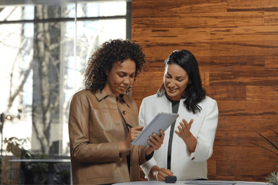 Two woman smiling, looking at business report
