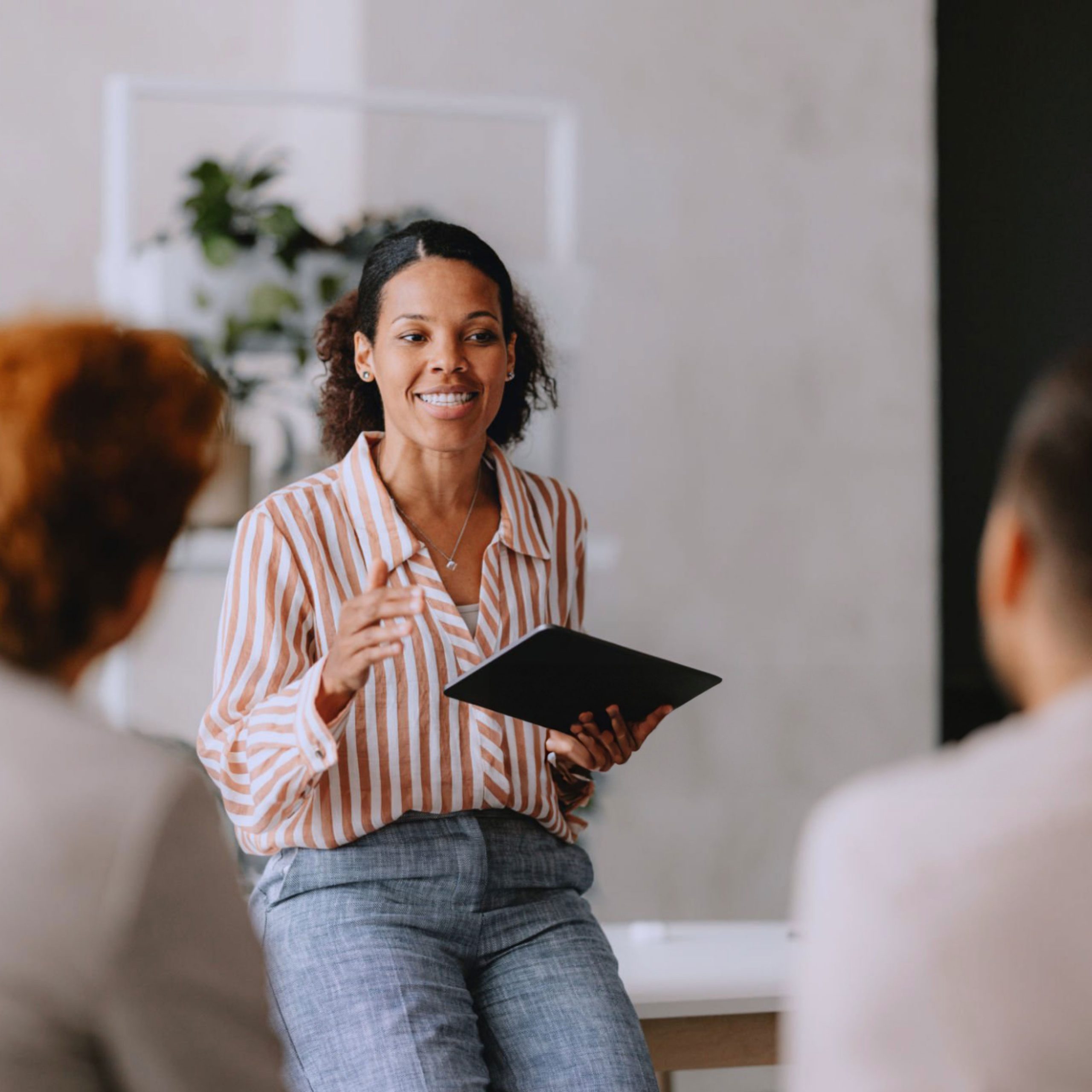 Women presenting in a meeting with tablet, smiling